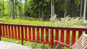 A wooden deck with two wooden chairs and a red railing. - 4 Star Holiday Home in Grisslehamn (Grisslehamn)