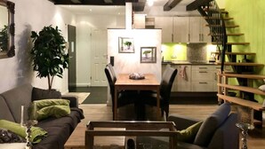 Ein modernes Wohnzimmer mit Essbereich, einer Treppe und einer Küche.