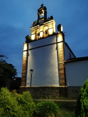 Una chiesa con una torre dell'orologio, illuminata da luci.