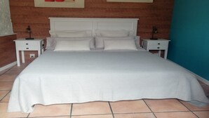 A bedroom with a large bed, two bedside tables, and two wall-mounted lamps.