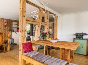 A rustic interior with a wooden dining table, bench, and stone wall.