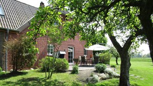 Una casa in mattoni con patio, un albero e un prato.