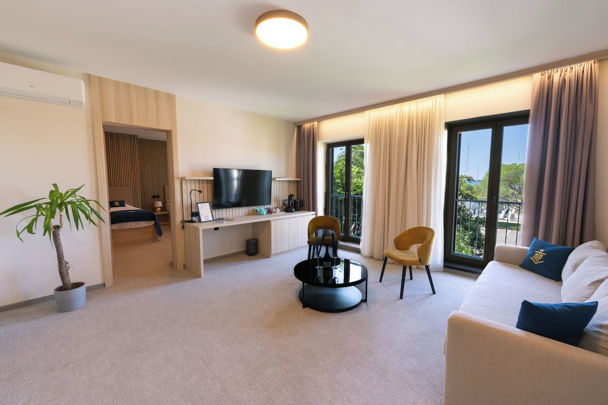 Una habitación de hotel moderna con una televisión de pantalla plana, un escritorio, un sofá cómodo y un balcón con vistas.