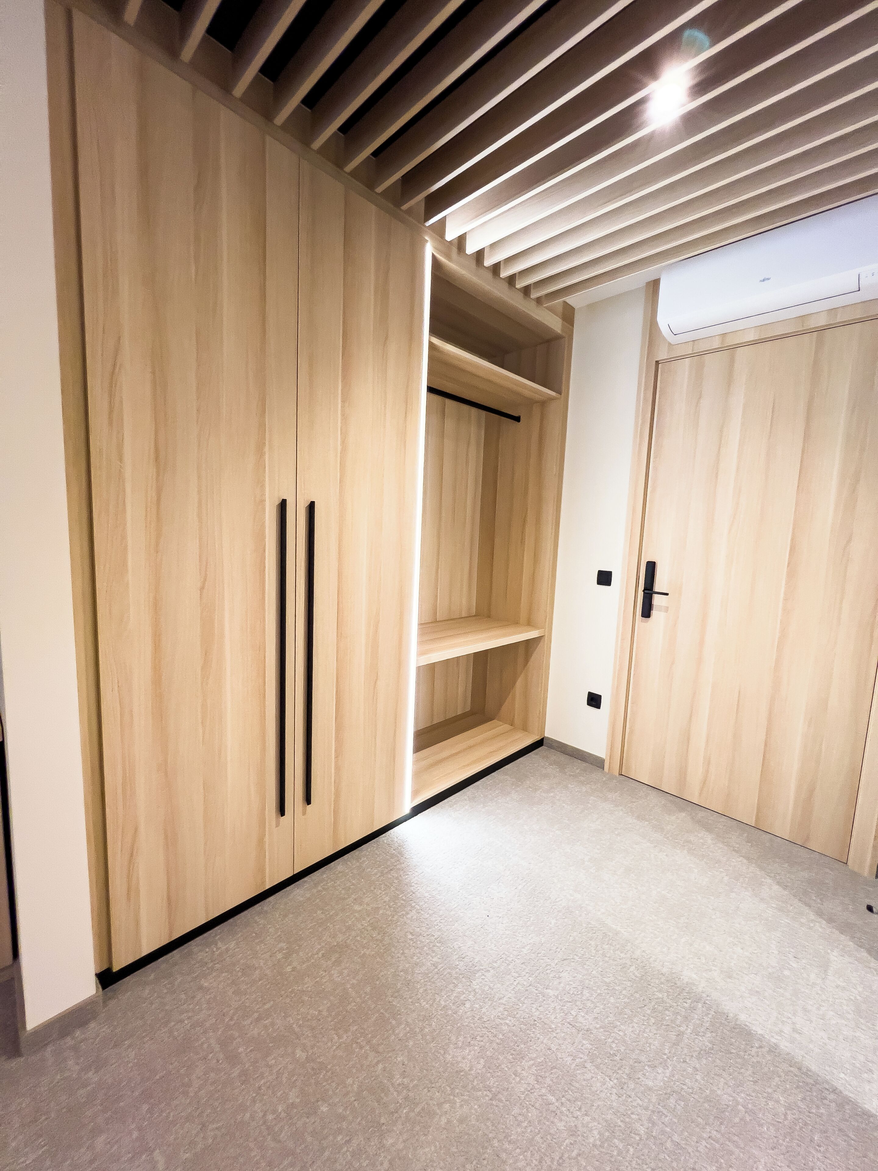 Ein Zimmer mit Holzschrank, Regaleinheit und Tür mit Griff.
