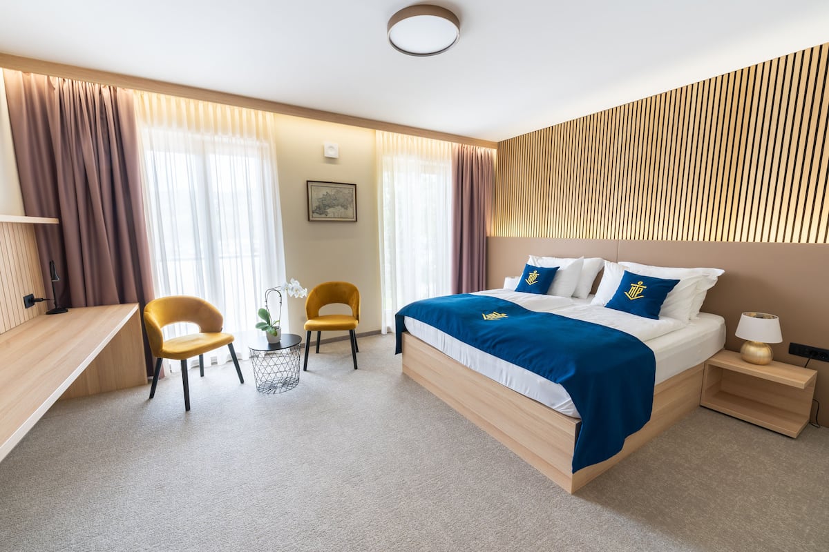 Una habitación de hotel moderna con una cama grande, un escritorio, una silla y una mesita.