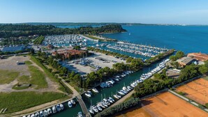 Une vue aérienne d’une marina où sont amarrés de nombreux bateaux, le tout entouré de verdure et de bâtiments.