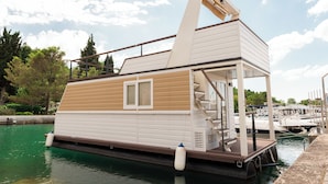 Une péniche dotée d’une terrasse, d’un escalier et d’une petite fenêtre.