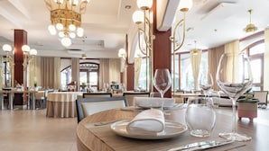 Un espace repas avec des tables rondes, des chaises et une variété d’articles de table, notamment des assiettes, des verres et des couverts.