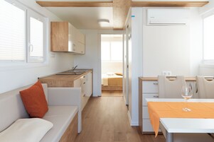 A modern, compact living space with a kitchenette, a dining area, and a bedroom.