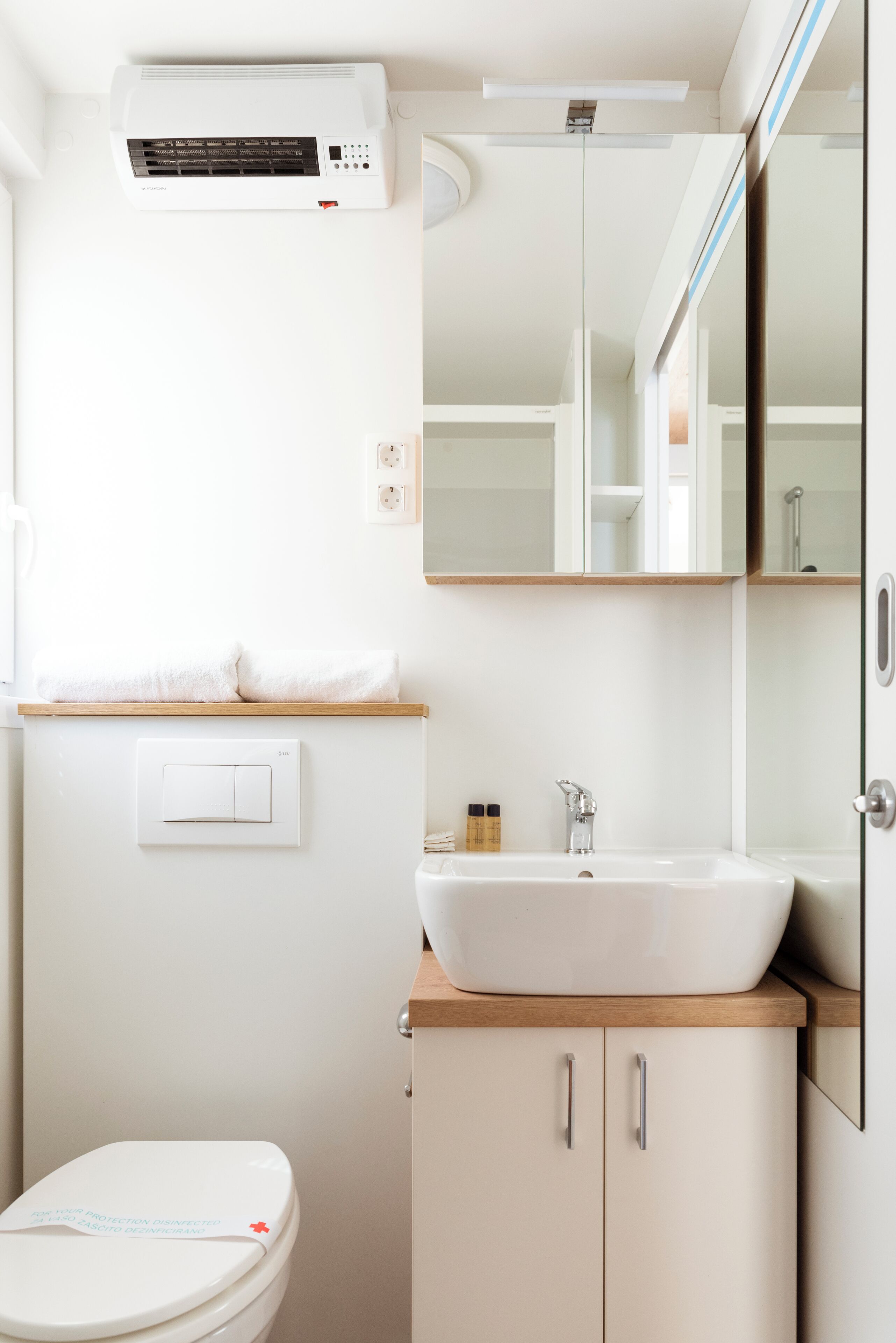 A modern bathroom with a white sink, mirror, and toilet.