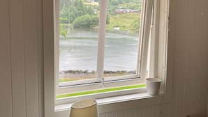 A window with a view of a lake, a house, and greenery. - 6 Person Holiday Home in Bjoa (Vindafjord)