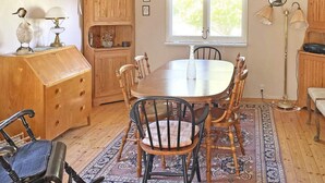 A dining area with a wooden table and chairs, a rug, and a window with curtains. - 6 Person Holiday Home in Vingaker (Vingåker)