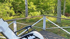 A deck with a white chair and a metal railing overlooking a wooded area. - 6 Person Holiday Home in Vingaker (Vingåker)