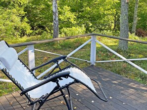 A deck with a white chair and a metal railing overlooking a wooded area. - 6 Person Holiday Home in Vingaker (Vingåker)