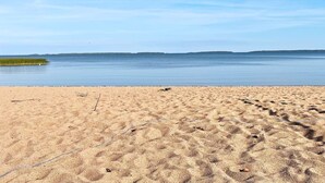 A beach with a clear sky, calm water, and distant land. - 6 Person Holiday Home in Vingaker (Vingåker)