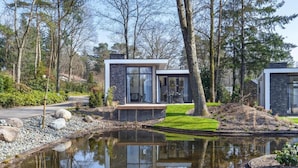 A modern house with a pond in front, surrounded by trees. - Luxury Stay Near Veluwe Park (Hoenderloo)