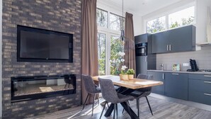 A modern kitchen with a built-in TV, a fireplace, and a dining area with a table and chairs. - Luxury Stay Near Veluwe Park (Hoenderloo)