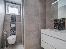 A modern bathroom with a toilet, a bidet, and a sink.