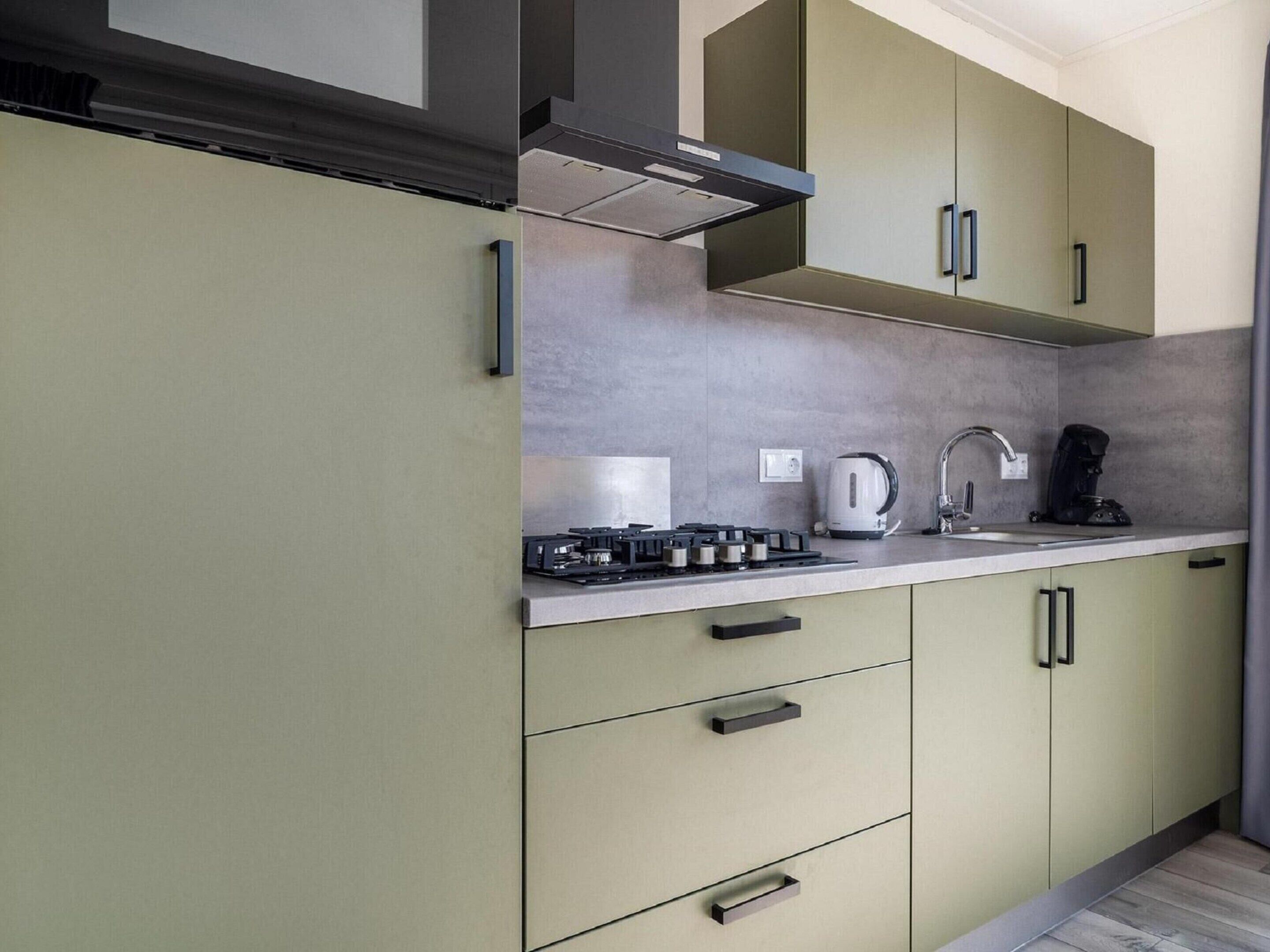 A modern kitchen with a gas stove, kettle, and coffee maker.