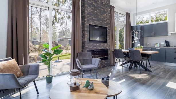 A modern living room with a fireplace, large windows, and a dining area. - Luxury Stay Near Veluwe Park (Hoenderloo)
