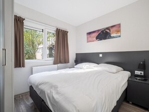 Relax in a serene space with a large bed, natural views, and a functional bedside area.