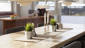 A modern dining area with a wooden table, potted plants, and pendant lights. - Loft Classiccar Modern Retreat (Gluecksburg)