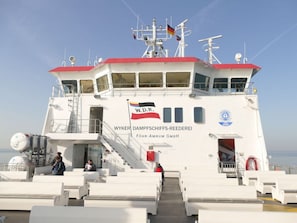 A ferry with a white exterior and red roof, featuring a flag and the name "W.D.R. WYKER DAMPPSCHIFFS-REEDEREI" on the side. - Favorite Place Modern Retreat (Wrixum)