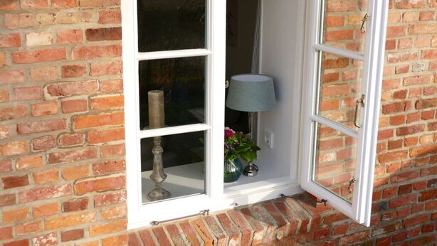 A corner window with a white frame, a lamp, and a vase with flowers. - Favorite Place Modern Retreat (Wrixum)