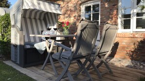 An outdoor seating area with a table and chairs, a striped canopy, and a brick building in the background. - Favorite Place Modern Retreat (Wrixum)