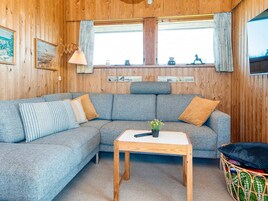 Una habitación acogedora con un sofá seccional gris, una mesa de centro de madera y una cesta de mimbre.