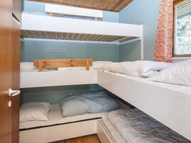 Habitación con literas, techo de madera y ventana con cortinas estampadas.