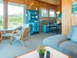 A cozy living room with a blue cabinet, wicker chairs, a round table, and a sofa. - 6 Person Holiday Home in Ringkobing-by Traum (Ringkobing)