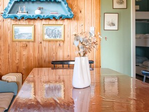 A wooden dining table with a white vase and dried flowers, a blue decorative shelf above, and framed pictures on the wall. - 6 Person Holiday Home in Ringkobing-by Traum (Ringkobing)