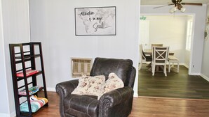 A leather armchair with floral cushions, a wooden bookshelf, and a framed inspirational quote on the wall. - Mema and Pa’s Place (Byrdstown)