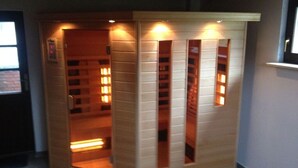 A sauna with a wooden exterior, multiple light panels, and a door. - Holiday Home \"baltic Sea Dream\" (Garz/Rügen)