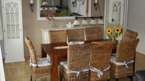 A dining area with wicker chairs, a wooden table, and a white cabinet. - Holiday Home \"baltic Sea Dream\" (Garz/Rügen)