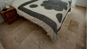 Un dormitorio con cama, mesita de noche, lámpara y ventana con cortinas.