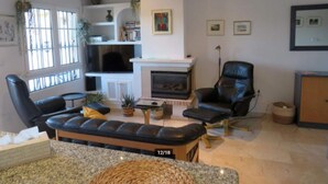 Una sala de estar amplia con chimenea, sillones de cuero y televisor.