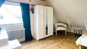 A room with a white wardrobe, a white chair, a radiator, and a window with curtains. - 4 Star Holiday Home in Goteborg (Gothenburg)