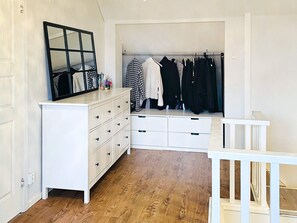 A white dresser with drawers, a mirror, and a clothing rack with various garments. - 4 Star Holiday Home in Goteborg (Gothenburg)