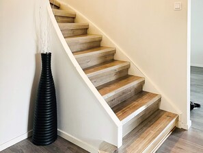Una escalera con escalones de madera y una pared blanca.