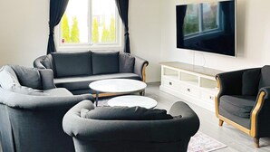 A modern living room with a sofa, armchairs, a coffee table, and a TV mounted on the wall. - 4 Star Holiday Home in Goteborg (Gothenburg)