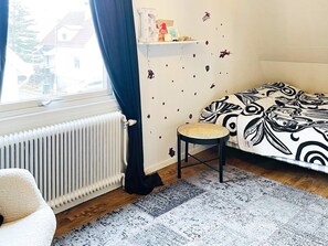 A room with a bed, a radiator, a window with curtains, a small stool, and a wall with decorative stickers. - 4 Star Holiday Home in Goteborg (Gothenburg)