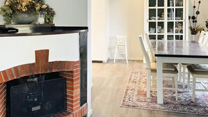 A modern kitchen with a brick fireplace, a dining area with a table and chairs, and a cabinet with glass doors. - 4 Star Holiday Home in Goteborg (Gothenburg)