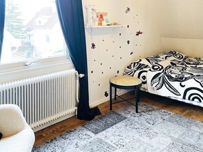A room with a bed, a radiator, a window with curtains, a small stool, and a wall with decorative stickers. - 4 Star Holiday Home in Goteborg (Gothenburg)