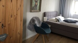 Une chambre à coucher avec un lit, une chaise, une armoire en bois et un tableau accroché au mur.