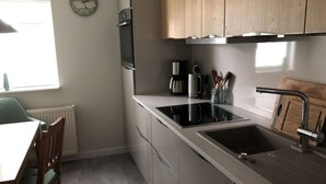 Une cuisine moderne dotée d’une cuisinière intégrée, d’un évier et d’armoires en bois.