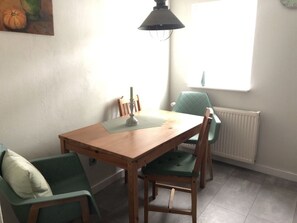 A dining area with a wooden table, green upholstered chairs, a pendant light, and a window with a view. - Guest House An der Truse (Brotterode-Trusetal)