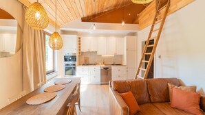 Eine moderne Küche mit weißen Schränken, einem Holzespeise Tisch mit Stühlen und einem braunen Ledersofa mit Kissen.