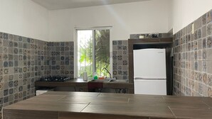 Une cuisine avec des carreaux décoratifs, une fenêtre, un réfrigérateur et un plan de travail.